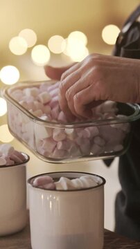 Woman Preparing Hot Cocoa In A Christmas-Decorated Kitchen And Decorating It With Marshmallows For Taste And Garnish, Vertical Video