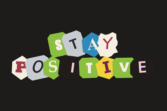 Stay positive text made with colorful ransom note style paper letters on a dark background