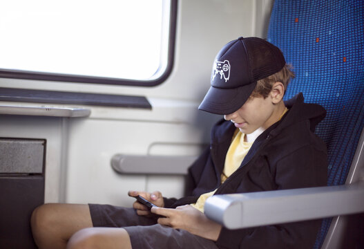 Teenager Traveling by Train Looking at Smartphone