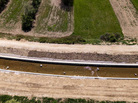 Aerial view showing channel widening for flood protection efforts in an agricultural area.