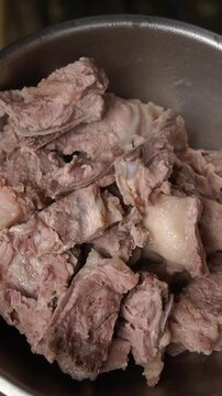 Cooking Thai pork rib soup with peanuts (Tom Soup Kra Dook Moo Thua Li Song). Blanching ribs, simmering with white pepper, coriander roots, peanuts, preserved radish, and seasonings.