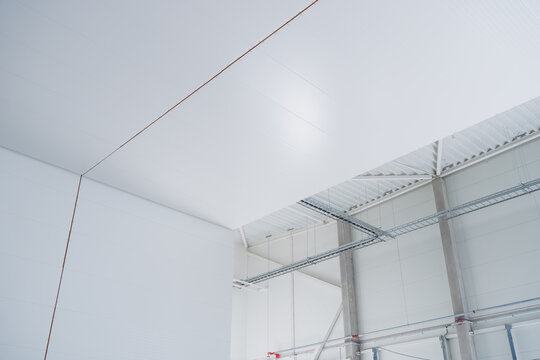 Insulated metal sandwich panels forming clean white interior partition walls and ceiling structures in a commercial industrial facility