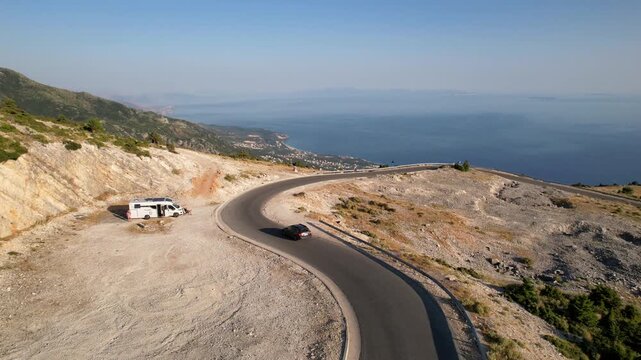 Сar driving on serpentine road in Panorama Llogora near Vlora and Zeus mountain in Albania, amazing scenery view. Aerial panoramic drone view from above, top view from drone. 
