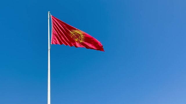 The red and yellow flag of Kyrgyzstan in the blue sky