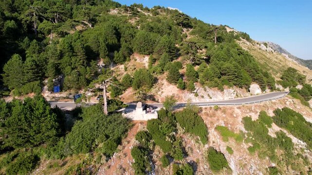 Man and woman on observation deck mountain on serpentine road in Panorama Llogora near Vlora and Zeus mountain, amazing scenery view. Aerial panoramic drone view from above, top view from drone. 
