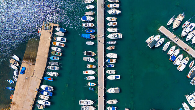 Aerial view of the marina in Rab, featuring numerous boats docked in rows along concrete piers in the clear turquoise Adriatic Sea, Rab, Primorje-Gorski Kotar, Croatia.