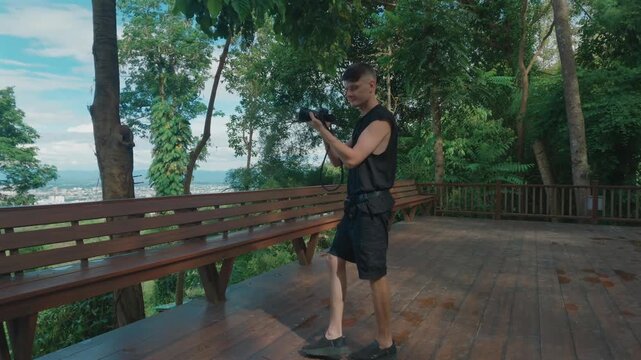 Male photographer filming with mirrorless camera at forest viewpoint in Chiang Mai, Travel videographer recording nature scenery with camera in Thailand 4k