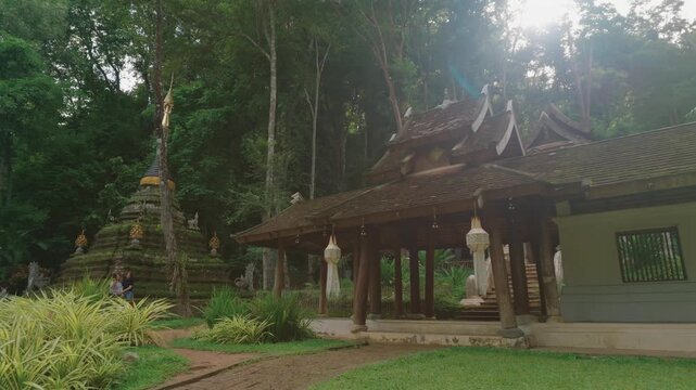 Entrance to Wat Phra Lat Buddhist temple by tropical forest in Chiang Mai Thailand, Traditional monastery architecture with peaceful garden courtyard and lush greenery at sunset 4k