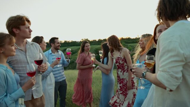 Large group enjoying conversation around outdoor dinner table. Concept of community dining, friendship networks, summer leisure and event catering.