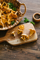 Fototapeta premium Fresh chanterelle mushrooms in a wicker basket and on a wooden cutting board in a rustic kitchen, gourmet cooking ingredients, healthy harvest, autumn food scene.