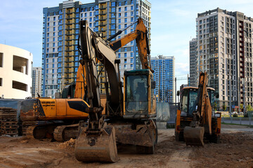 Heavy construction machinery on a site against modern high-rise buildings, urban development and civil engineering concept © Алина Неборская