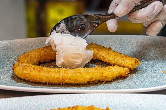  Professional chef hands plating a gourmet grilled banana dessert with vanilla ice cream and rich chocolate sauce.