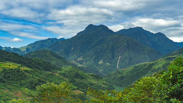 Lush green mountain landscape under dramatic clouds in northern Vietnam