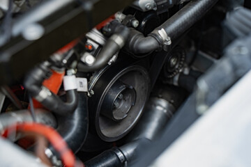Serpentine belt and pulley system inside a high performance vehicle engine bay showing mechanical...