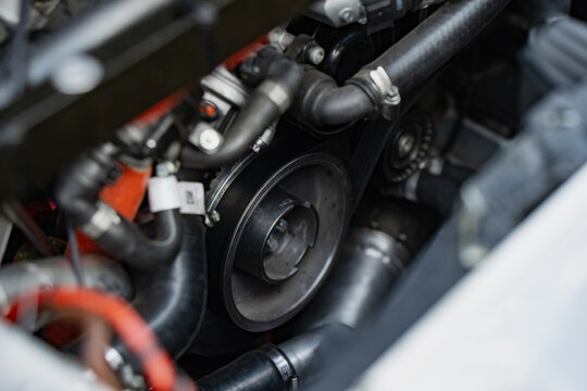 Serpentine belt and pulley system inside a high performance vehicle engine bay showing mechanical components and routing