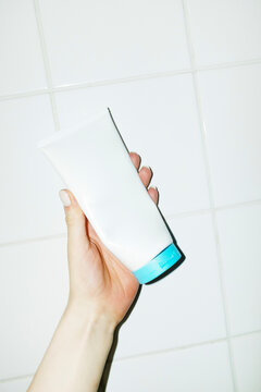 Hand holding cosmetic beauty product lotion cream tube with blue cap