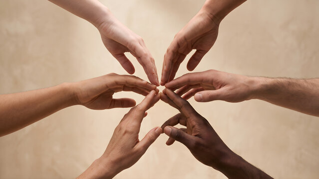 A diverse group of hands of different skin tones come together in a circle, symbolizing unity, cooperation, and inclusivity