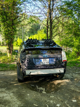 A damaged Toyota Prius hybrid car with a large dent in the fender and a missing bumper is parked in the woods near Tbilisi; accident damage and body damage to the car, Georgia 10.04.2025