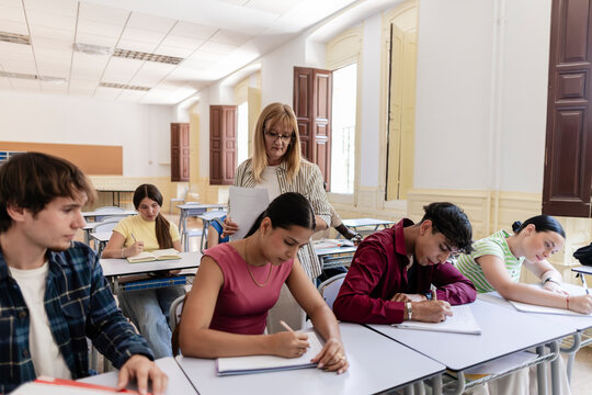 Teacher observing diverse students during classroom exam