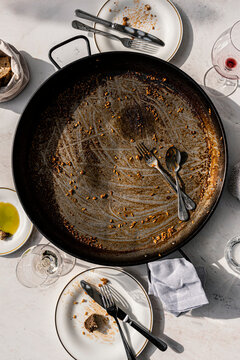 Empty paella pan and dirty plates after a traditional Spanish meal