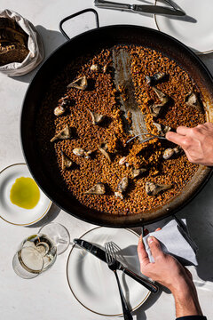 Chef hands serving fresh hot rice from a paella pan