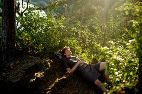 Young Man Relaxes on a Rocky Ledge in Nature During Daylight