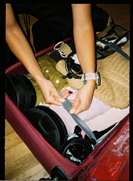 Hands securing luggage straps inside a packed suitcase