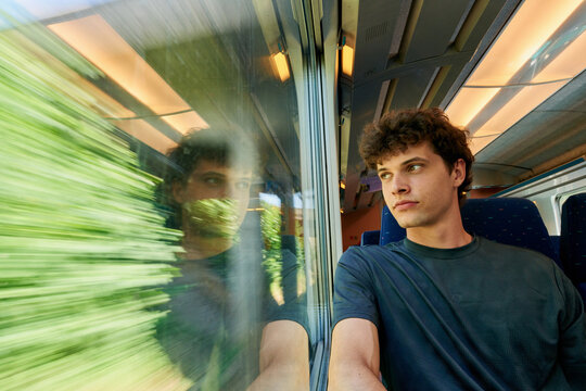 Young Man Gazes out of Train Window During a Journey