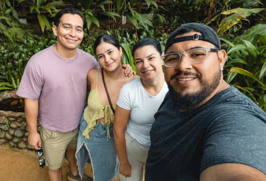 Four happy adults taking selfie in lush green park