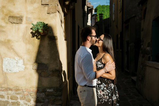 A Romantic Couple kissing on a walk in town at sunset