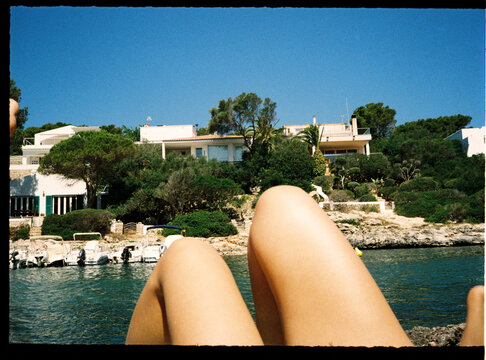 Legs relaxing by coastline villas and clear turquoise water