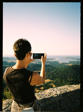 Person capturing scenic landscape view with smartphone
