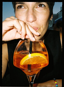 Person enjoying a refreshing orange cocktail during leisure time