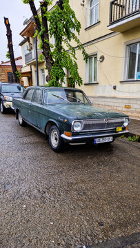 Green vintage GAZ-24 Volga from the 1980s with weathered paint on a wet road in Telavi; historic Soviet passenger car, Kakheti region, Telavi, Georgia 11.04.25