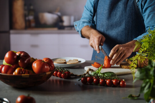 Man chopping fresh tomatoes for preparing a healthy meal