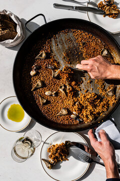 Chef hands serving fresh hot rice from a paella pan