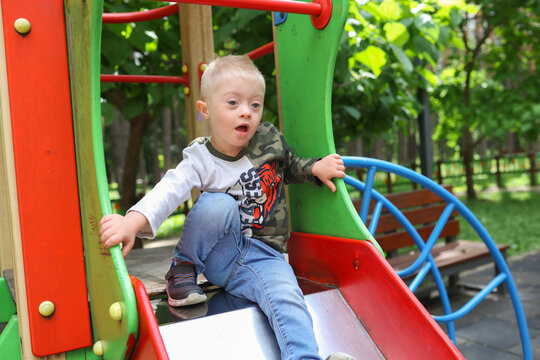 A boy with Down syndrome is walking in the park.