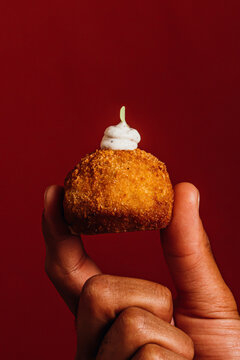Hand holding a single crispy Spanish gourmet croquette 