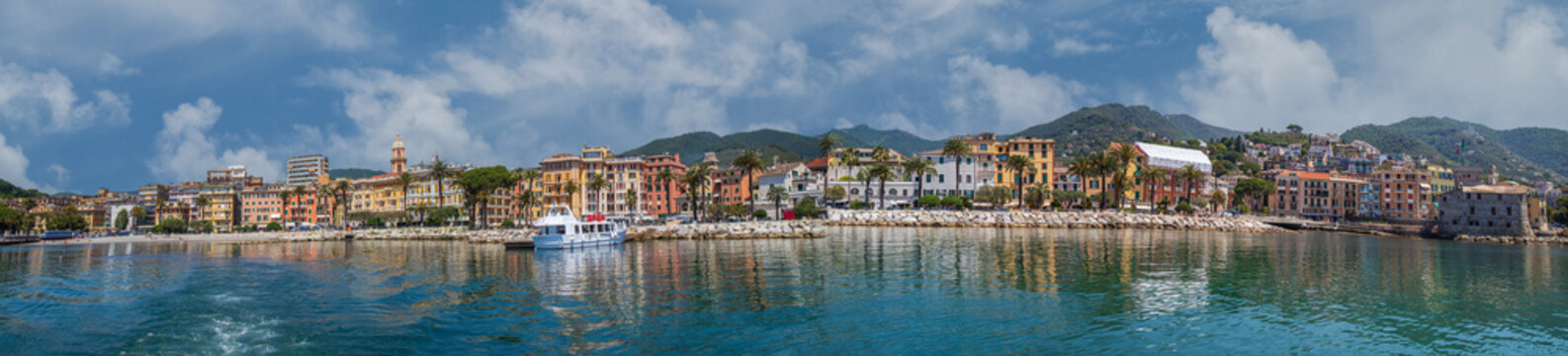 Panoramic view with the famous promenade and the harbor of the city of Rapallo, on the Golfo del Tigullio, Liguria region, Italy. Colorful Ligurian-style buildings, palm trees, views of the calm sea.