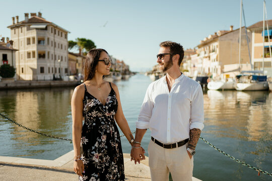A couple walking hand in hand by the town harbour during vacation