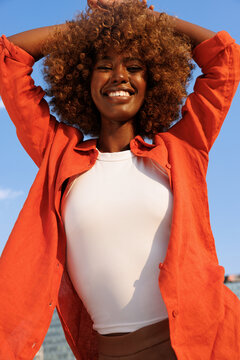 Portrait of woman smiling in orange against blue sky