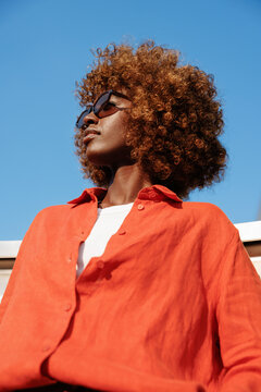 Woman portrait wearing sunglasses and orange shirt outdoors