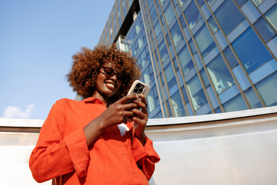 Woman using smartphone beside modern glass office building