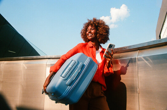 Woman carries blue suitcase and smartphone travel film photo