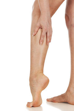 Female legs with vascular stars on the skin, isolated. Woman touches her shin with her hand