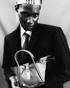 Black and white portrait of fashion model holding handbag.