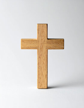Wooden cross standing upright on clean white surface, minimalist Christian symbolism, religion, feith. Close-up.