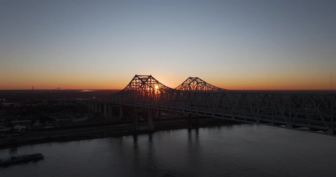 First light through a bridge as a barge approaches on the Mississippi River in New Orleans
