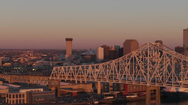 Caesars Superdome peeking behind downtown buildings with a Mississippi River bridge in the foreground