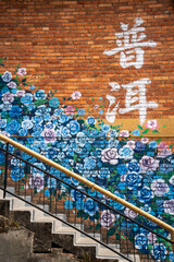 Chinese character floral mural on brick wall beside staircase © ThaiKhanh